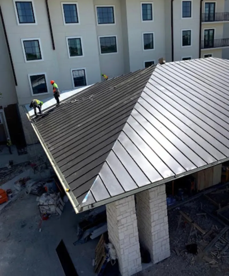 Crew installing standing seam metal roof panels on a commercial project in Yorktown